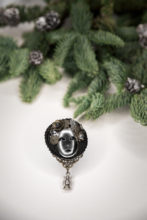 Rankų darbo sagė su moters veidu, hematitais